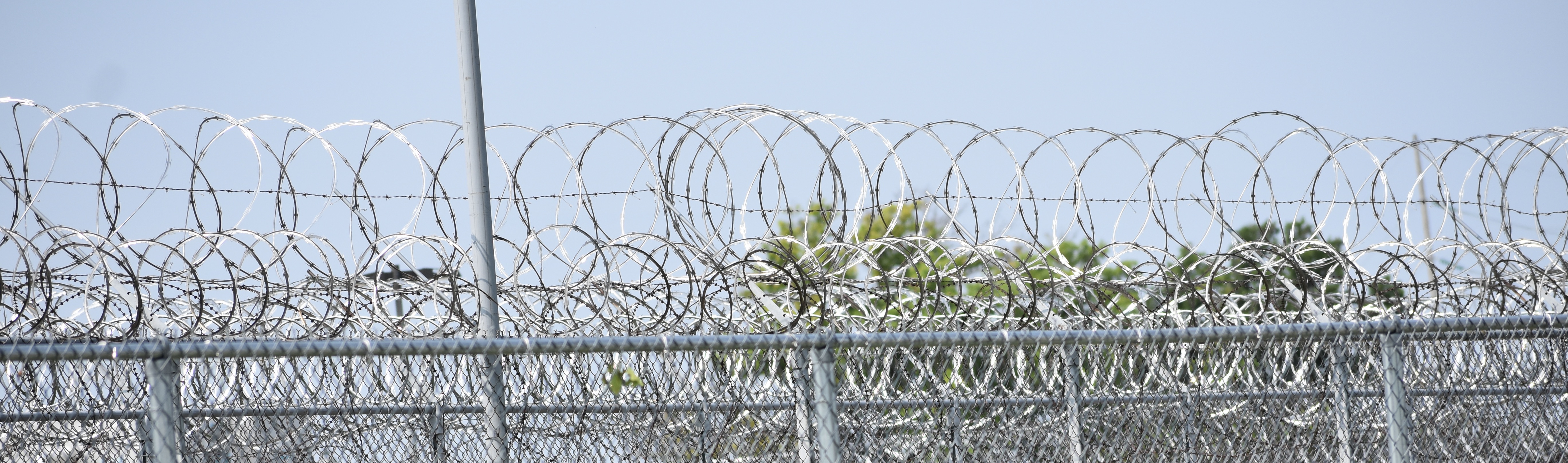 Concertina wire across the top of a barbed wire perimeter fence